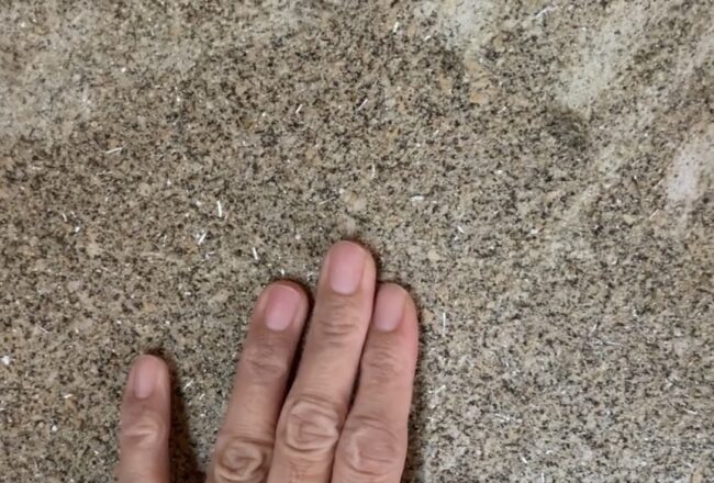 砂壁（繊維壁）を手で触っている様子を撮影した写真